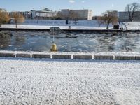 a fire hydrant near the edge of a river covered in snow next to a dock