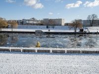 a fire hydrant near the edge of a river covered in snow next to a dock