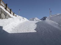 a ski slope in the snow with a road and some poles and trees in the foreground