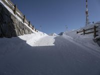 a ski slope in the snow with a road and some poles and trees in the foreground