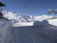 a snowy street with a ski lift in the background and another mountain behind it,