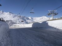 a snowy street with a ski lift in the background and another mountain behind it,