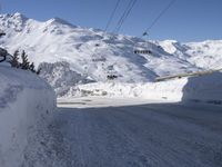 a snowy street with a ski lift in the background and another mountain behind it,