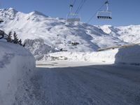 a snowy street with a ski lift in the background and another mountain behind it,