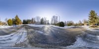 a snow covered road with trees and houses in the background on a sunny day with snow