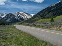 the road is paved with yellow markings and has a snowy mountain range in the background