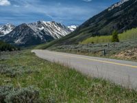 the road is paved with yellow markings and has a snowy mountain range in the background