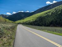 the road is paved with yellow markings and has a snowy mountain range in the background