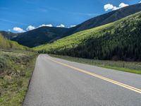 the road is paved with yellow markings and has a snowy mountain range in the background