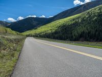 the road is paved with yellow markings and has a snowy mountain range in the background