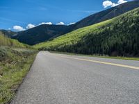 the road is paved with yellow markings and has a snowy mountain range in the background