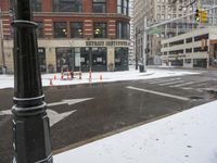 the street and traffic signal are in the snow on the sidewalk of a city street