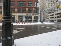 the street and traffic signal are in the snow on the sidewalk of a city street