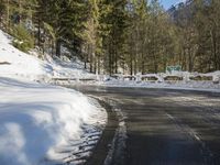 snow covers the top of a fence along a snow covered road in the middle of mountains