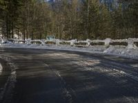 snow covers the top of a fence along a snow covered road in the middle of mountains