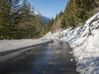 snow covers the top of a fence along a snow covered road in the middle of mountains