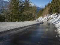 snow covers the top of a fence along a snow covered road in the middle of mountains