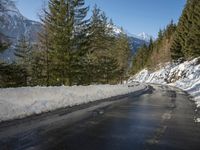 snow covers the top of a fence along a snow covered road in the middle of mountains