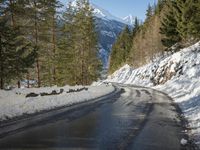 snow covers the top of a fence along a snow covered road in the middle of mountains