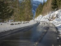 snow covers the top of a fence along a snow covered road in the middle of mountains