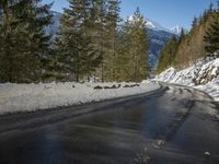 snow covers the top of a fence along a snow covered road in the middle of mountains