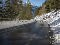 snow covers the top of a fence along a snow covered road in the middle of mountains