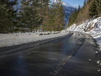 snow covers the top of a fence along a snow covered road in the middle of mountains