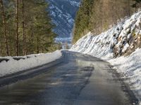 snow covers the top of a fence along a snow covered road in the middle of mountains