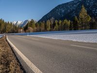 a highway next to the mountain that has snow on top of it and is closed