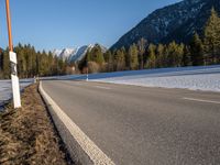 a highway next to the mountain that has snow on top of it and is closed