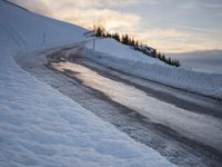 snow covered road beside large mountain in distance and sky in the background with clouds overhead