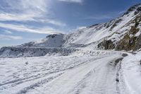 a long dirt road that is covered in snow and snow covered ground and rocks and snow covered mountain