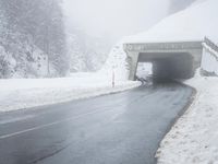 a snow covered road leading through a tunnel to an overpass on top of the mountain