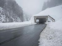 a snow covered road leading through a tunnel to an overpass on top of the mountain