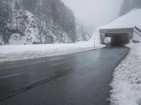 a snow covered road leading through a tunnel to an overpass on top of the mountain