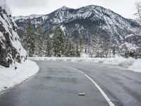 there is a snow covered road with the mountains in the background in the background,