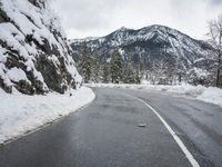 there is a snow covered road with the mountains in the background in the background,