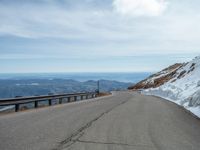 an empty road and a hill overlook the view of mountains and clouds and blue sky