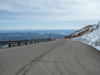 an empty road and a hill overlook the view of mountains and clouds and blue sky