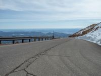 an empty road and a hill overlook the view of mountains and clouds and blue sky