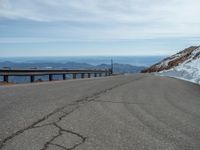 an empty road and a hill overlook the view of mountains and clouds and blue sky