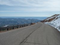 an empty road and a hill overlook the view of mountains and clouds and blue sky