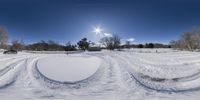 an intersection is shown in the snow with bright sun in background and blue sky above