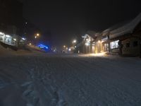 the snow is falling on the street in the middle of town at night, and no one is still skiing