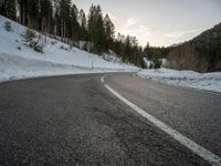 a car is parked on an open road surrounded by trees and snow covered hills a few km north