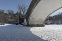 an old, snow covered road passes under a stone arch bridge in the snow in this image