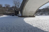 an old, snow covered road passes under a stone arch bridge in the snow in this image