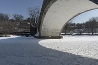 an old, snow covered road passes under a stone arch bridge in the snow in this image