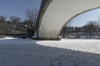 an old, snow covered road passes under a stone arch bridge in the snow in this image