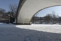 an old, snow covered road passes under a stone arch bridge in the snow in this image